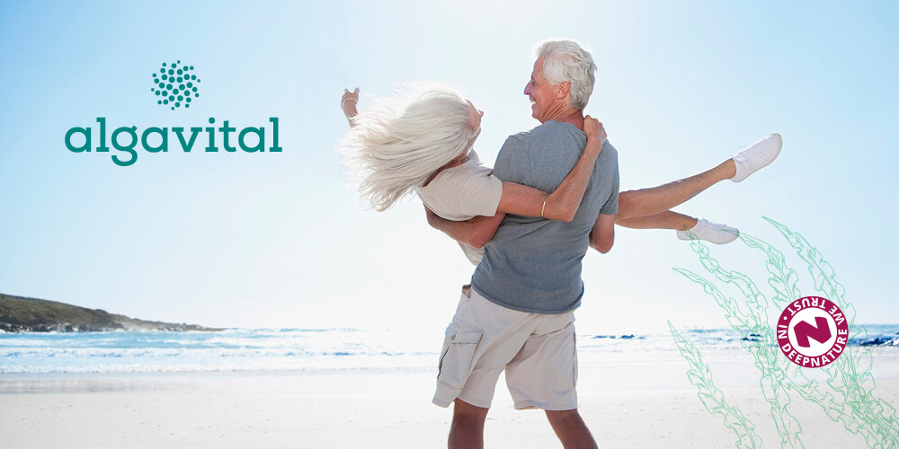 Ein sehr glückliches älteres Ehepaar, das im Sonnenschein am Meer tanzt